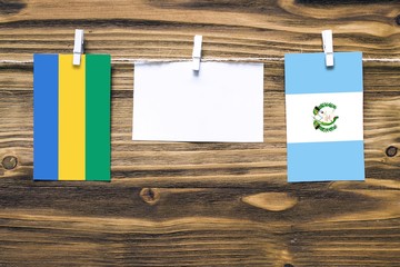 Hanging flags of Gabon and Guatemala attached to rope with clothes pins with copy space on white...