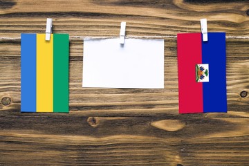 Hanging flags of Gabon and Haiti attached to rope with clothes pins with copy space on white note...