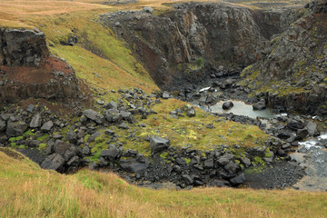 Hengifoss Canyon with the Hengifoss Waterfall, the third highest waterfall in Iceland is surrounded by basaltic strata with red layers of clay between the basaltic layers