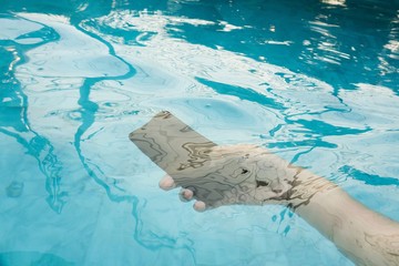 A modern black smartphone makes a splash as it is dropped in the water to test its waterproof...
