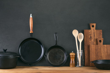 Kitchen utensils dark background with cast iron black kitchenware