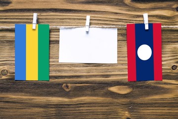 Hanging flags of Gabon and Laos attached to rope with clothes pins with copy space on white note...