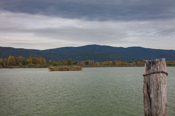 landscape with lake and mountains lake shore pier pole coning ou too the water moody cloudy skies