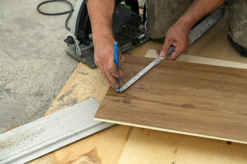Worker measures and saws off fragments of steps for stairs