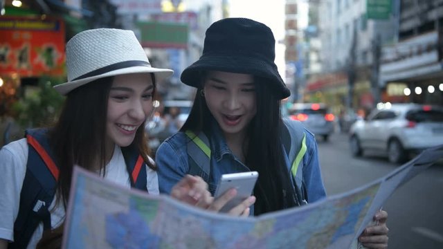 Travel concept. Beautiful girls are reading the map on the roadside. 4k Resolution.