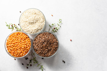 Red lentils, flax seeds and sesame seeds with peppercorn and thyme twigs on white marble table top view, copy space for your text.  Template healthy food blog social media.