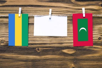 Hanging flags of Gabon and Maldives attached to rope with clothes pins with copy space on white...