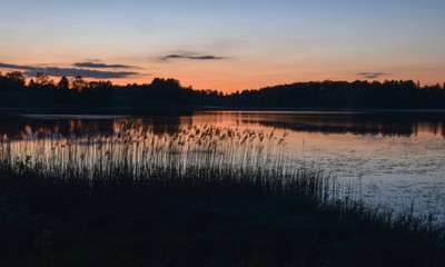 sunset landscape over the lake, dark tree silhouettes and orange skies