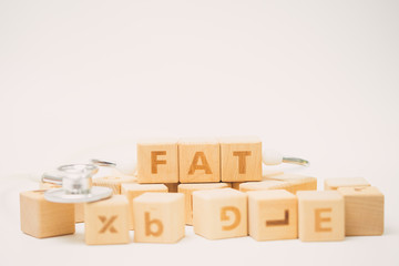 Fototapeta premium FAT word on wooden cube and stethoscope.