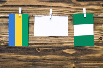 Hanging flags of Gabon and Nigeria attached to rope with clothes pins with copy space on white note...
