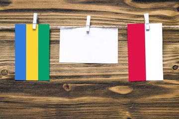 Hanging flags of Gabon and Poland attached to rope with clothes pins with copy space on white note...