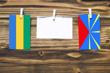 Hanging flags of Gabon and Reunion attached to rope with clothes pins with copy space on white note...