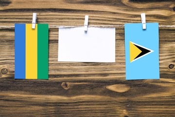 Hanging flags of Gabon and Saint Lucia attached to rope with clothes pins with copy space on white...