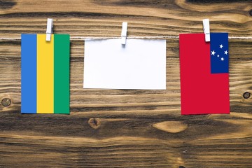 Hanging flags of Gabon and Samoa attached to rope with clothes pins with copy space on white note...