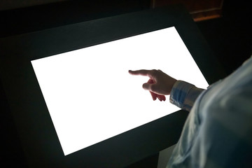 Woman hand using white blank interactive touchscreen display of electronic multimedia kiosk in dark room - scrolling and touching - close up view. Mock up, copyspace, template and technology concept - obrazy, fototapety, plakaty