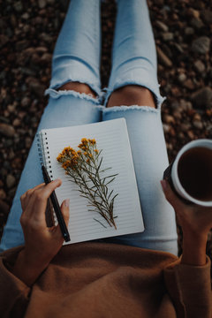 Woman holding spiral book with yellow flowers