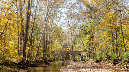 autumn landscape with a stone bridge over a stream