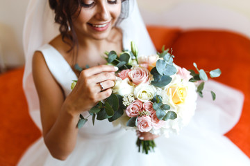 Wedding bouquet in bride's hands. Stylish, elegant bridal bouquet. Beautiful smiling bride showing off her beautiful  flowers bouquet. Wedding day. Floristy.