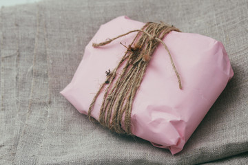 Soft pouch wrapped in craft paper and tie cord. Crumpled paper background texture. Delivery service. Online shopping.