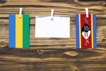 Hanging flags of Gabon and Swaziland attached to rope with clothes pins with copy space on white...