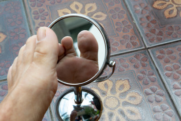 Person looking at the sole of the foot in a mirror.