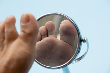 Person looking at the sole of the foot in a mirror.