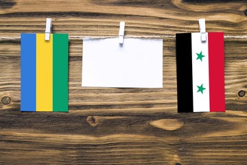 Hanging flags of Gabon and Syria attached to rope with clothes pins with copy space on white note...
