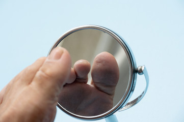 Person looking at the sole of the foot in a mirror.