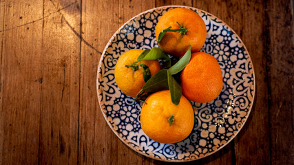 Above view of a beautiful plate with orange fruits on a wooden table.