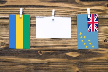 Hanging flags of Gabon and Tuvalu attached to rope with clothes pins with copy space on white note...