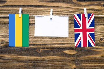 Hanging flags of Gabon and United Kingdom attached to rope with clothes pins with copy space on...
