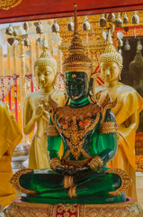 Stunning emerald buddha sculpture in a peaceful meditative posture in a golden Buddha temple