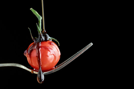 Styling food on a fork with a single tomato, mozzarella ball, basil, balsamic vinegar