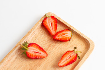 Halves of fresh strawberries on a wooden plate  Juicy strawberries