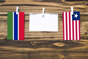 Hanging flags of Gambia and Liberia attached to rope with clothes pins with copy space on white...