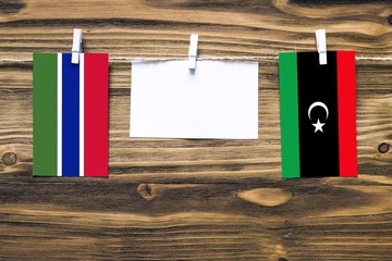 Hanging flags of Gambia and Libya attached to rope with clothes pins with copy space on white note...