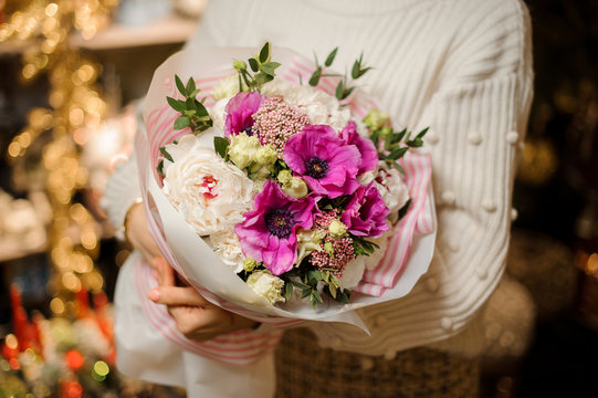 Girl holding a bouquet with purple pink and white peony roses decorated with green leaves
