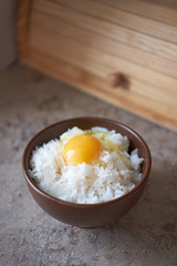 Tamago kake gohan with raw egg in bowl, vertical orientation