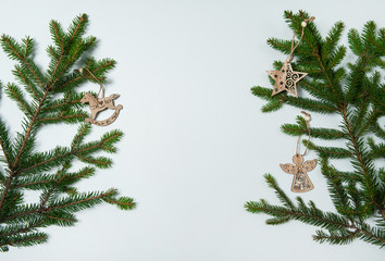 Obraz premium Christmas composition. The border is made of spruce branches, wooden toys in the form of an angel, a star and a rocking horse on a white background. Christmas, winter, New year.