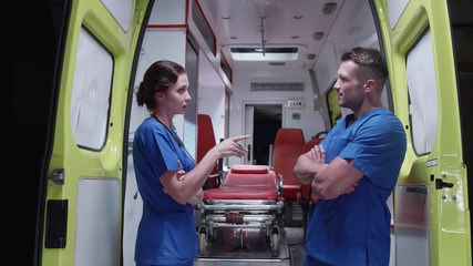 Nurse talk to corpsman over ambulance car at night.