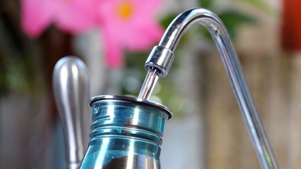 Refilling a reusable metal water bottle at sink
