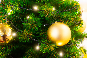 Merry Christmas and happy new year concept, Closeup of golden bauble hanging from a decorated tree with bokeh, Xmas holiday background.copy space.