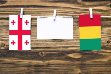 Hanging flags of Georgia and Guinea attached to rope with clothes pins with copy space on white...
