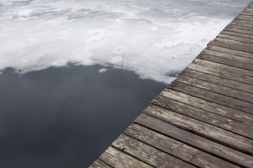 Melting lake ice in spring with a part of a jetty showing