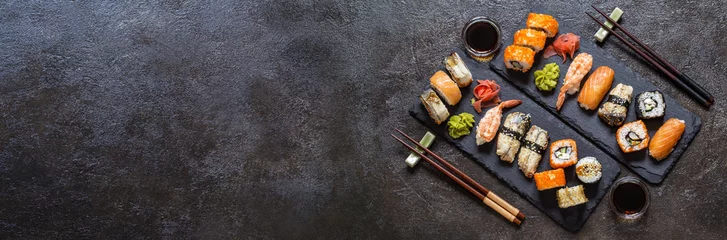 Foto op Plexiglas Sushi bar Sushibroodjes met rijst en vis, sojasaus op een donkere stenen ondergrond
