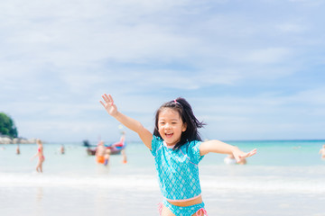 Little asian girl running on sea sand on the beach.Vacation and relax concept.Playful active kid on beach in summer vacation.