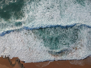 Sand beach aerial, top view of a beautiful sandy beach aerial shot with the blue waves rolling into the shore