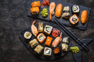 sushi rolls with rice and fish, soy sauce on a dark stone background