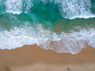 Sand beach aerial, top view of a beautiful sandy beach aerial shot with the blue waves rolling into the shore