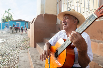 Local man singing and playing his guitar in the Plaza Mayor of Trinidad, Cuba in late afternoon. Model released